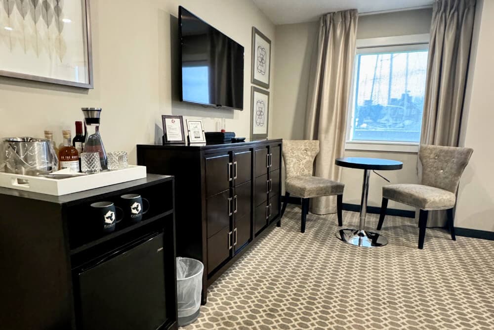 A dresser, flat scrren TV, mini fridge and coffee center, and a sitting area with 2 chairs and a small table.