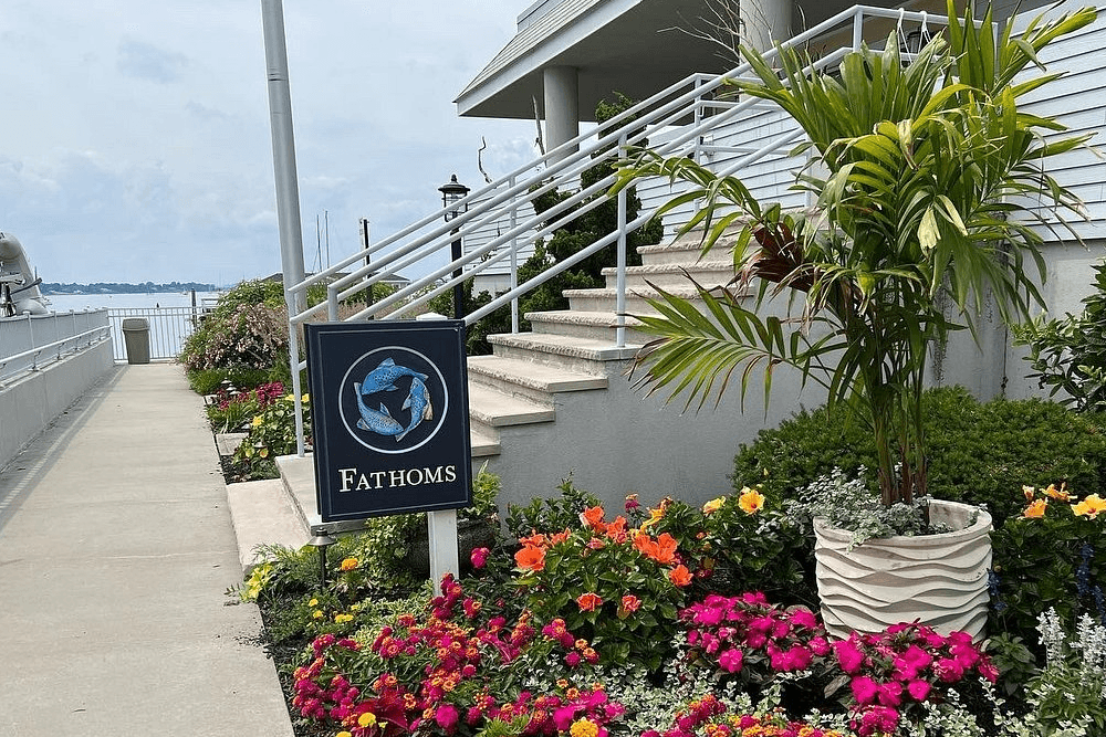bridesmaids in blue formal dresses leaning over a railing looking out onto the water