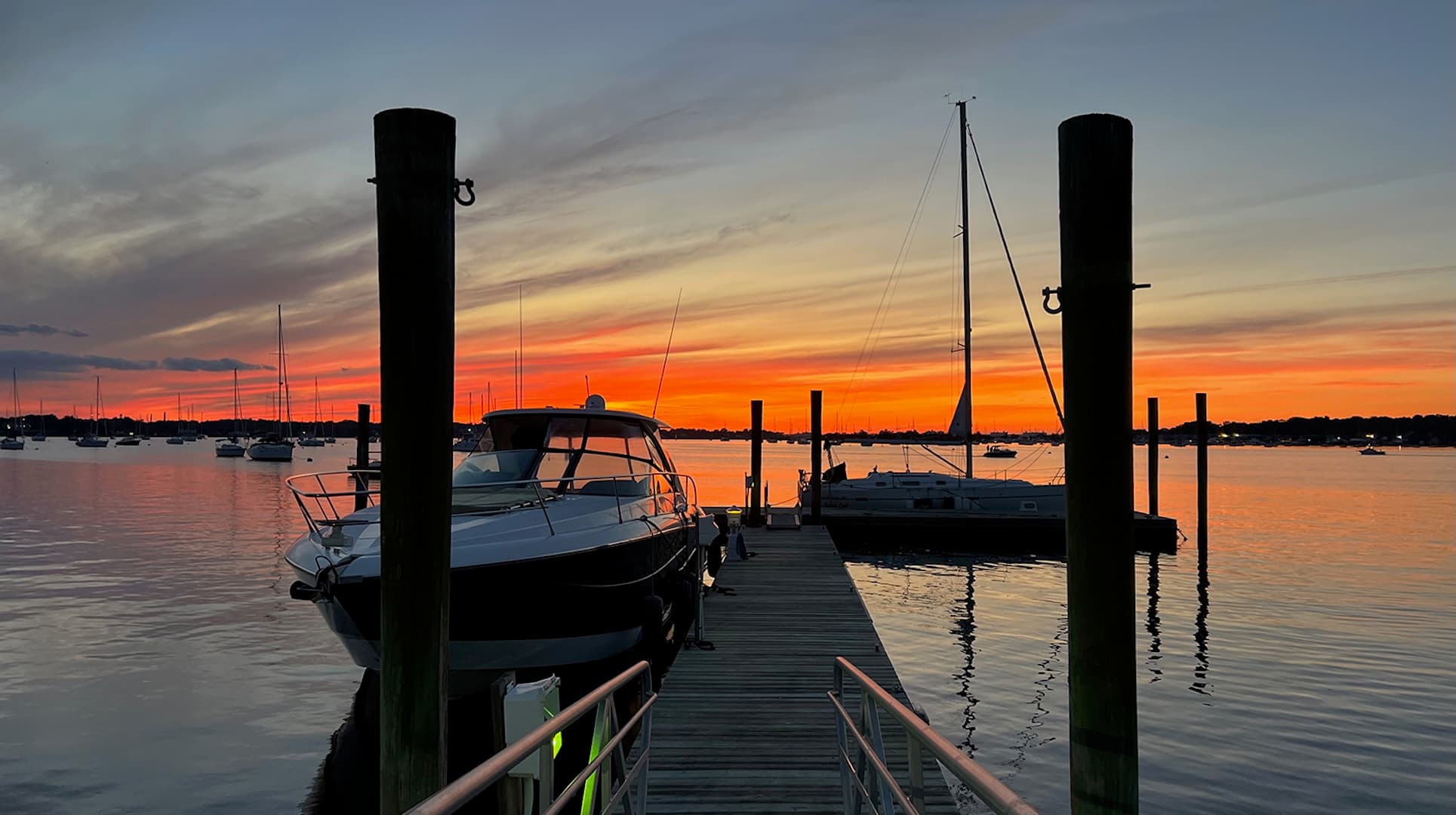 A serene sunset over a marina with boats docked and vibrant colors reflecting on the water.